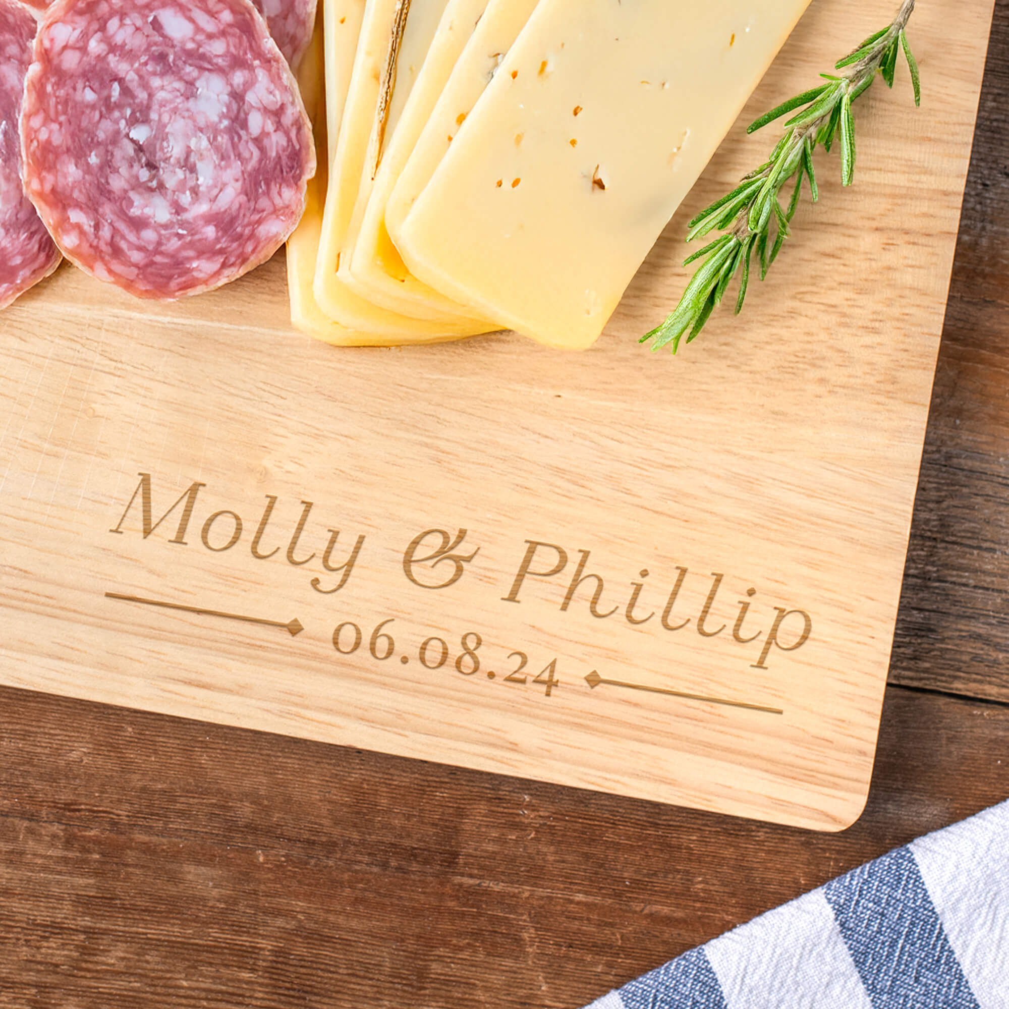 Personalized maple cutting board engraved with couple’s names and date, displayed with stacked cutting boards on a kitchen countertop.