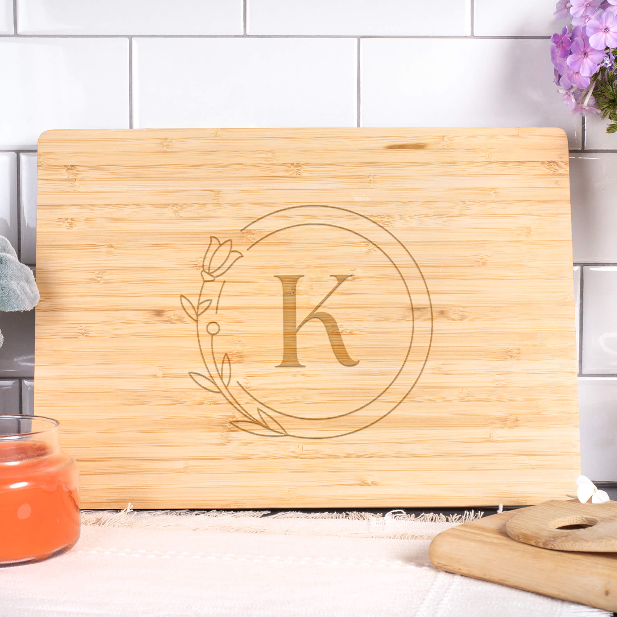 Personalized bamboo cutting board with circle monogram K, styled on a kitchen counter