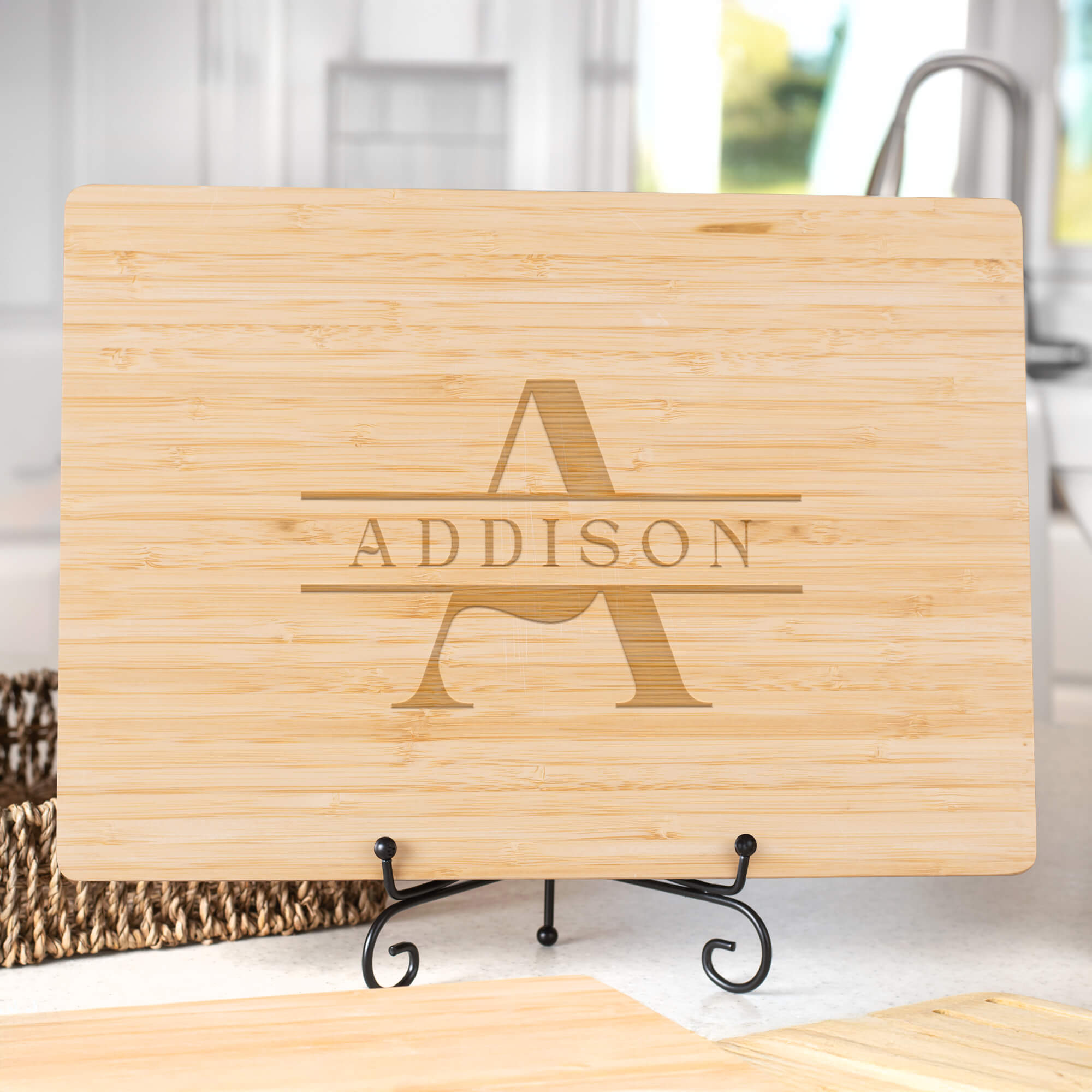 Bamboo cutting board with classic A and ADDISON monogram displayed on a stand in a kitchen setting