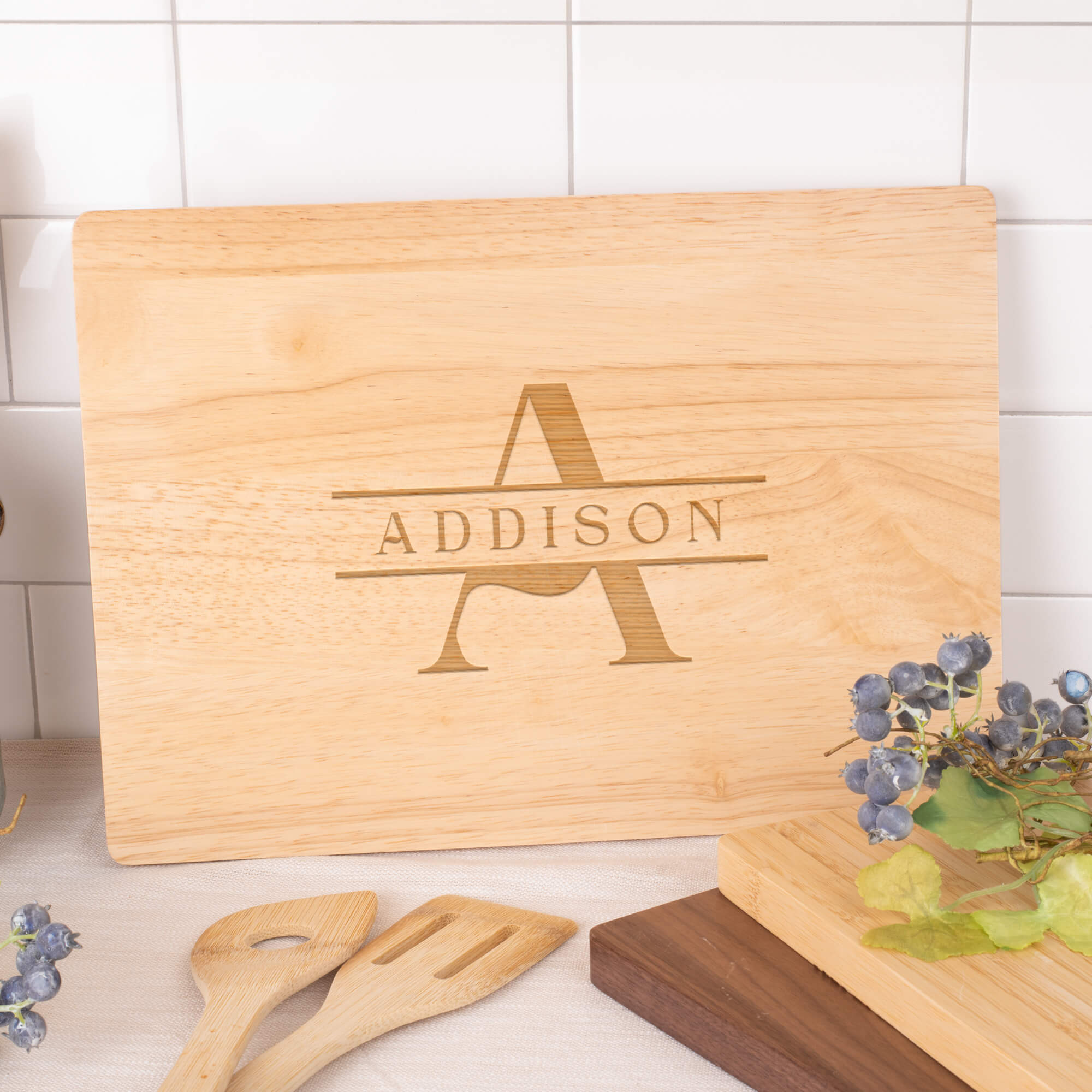 Personalized maple cutting board engraved with classic A and ADDISON monogram, styled on a kitchen counter