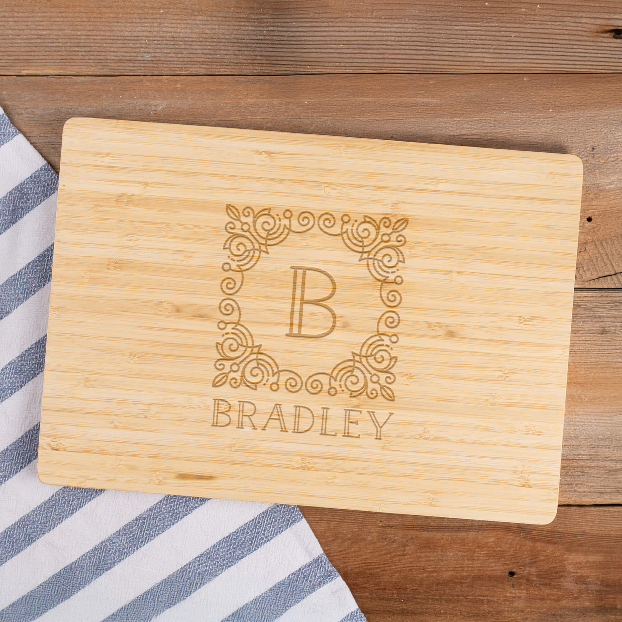Personalized bamboo cutting board featuring engraved B monogram and Bradley family name, styled on wooden surface