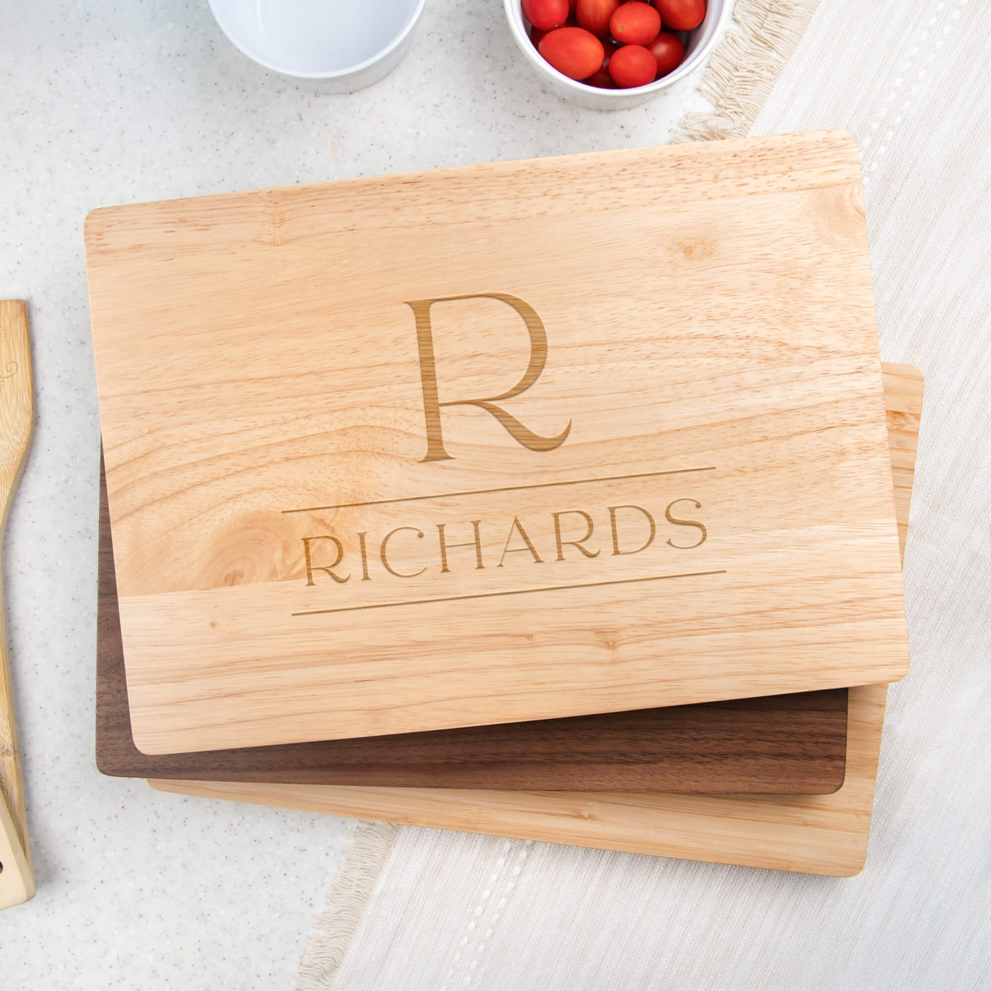 Maple paddle cutting board engraved with stacked serif R monogram and Richards family name displayed on a stand in a kitchen
