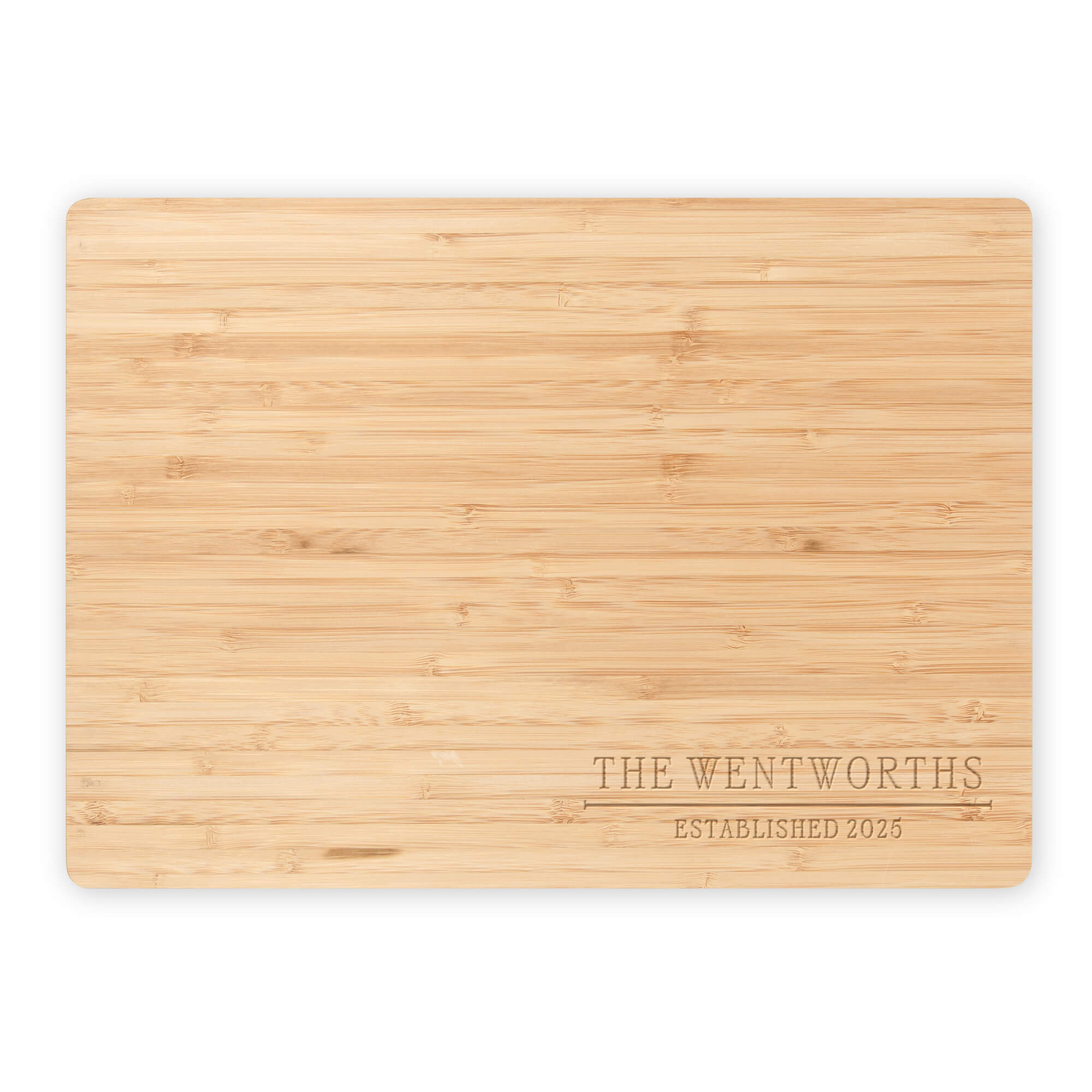 Flat lay of engraved bamboo cutting board with “The Wentworths Established 2025” on a white background, showing its smooth wood grain.