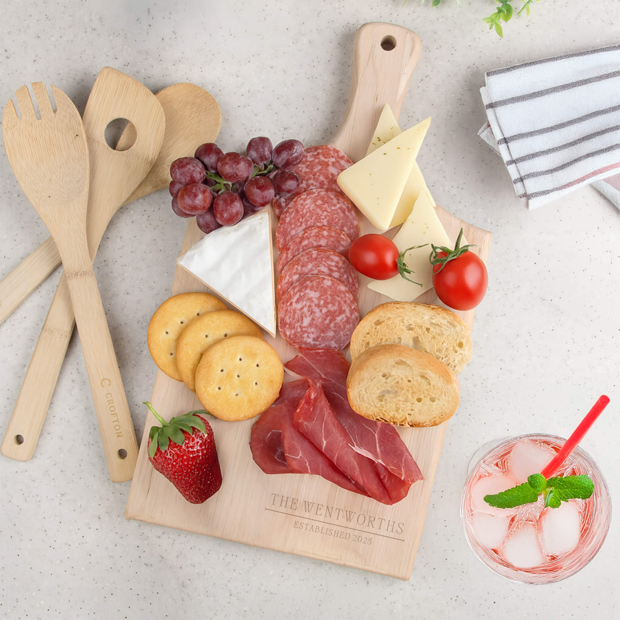 Paddle-style cutting board engraved with “The Wentworths Established 2025,” styled as a charcuterie board with cheese, crackers, and fruit.