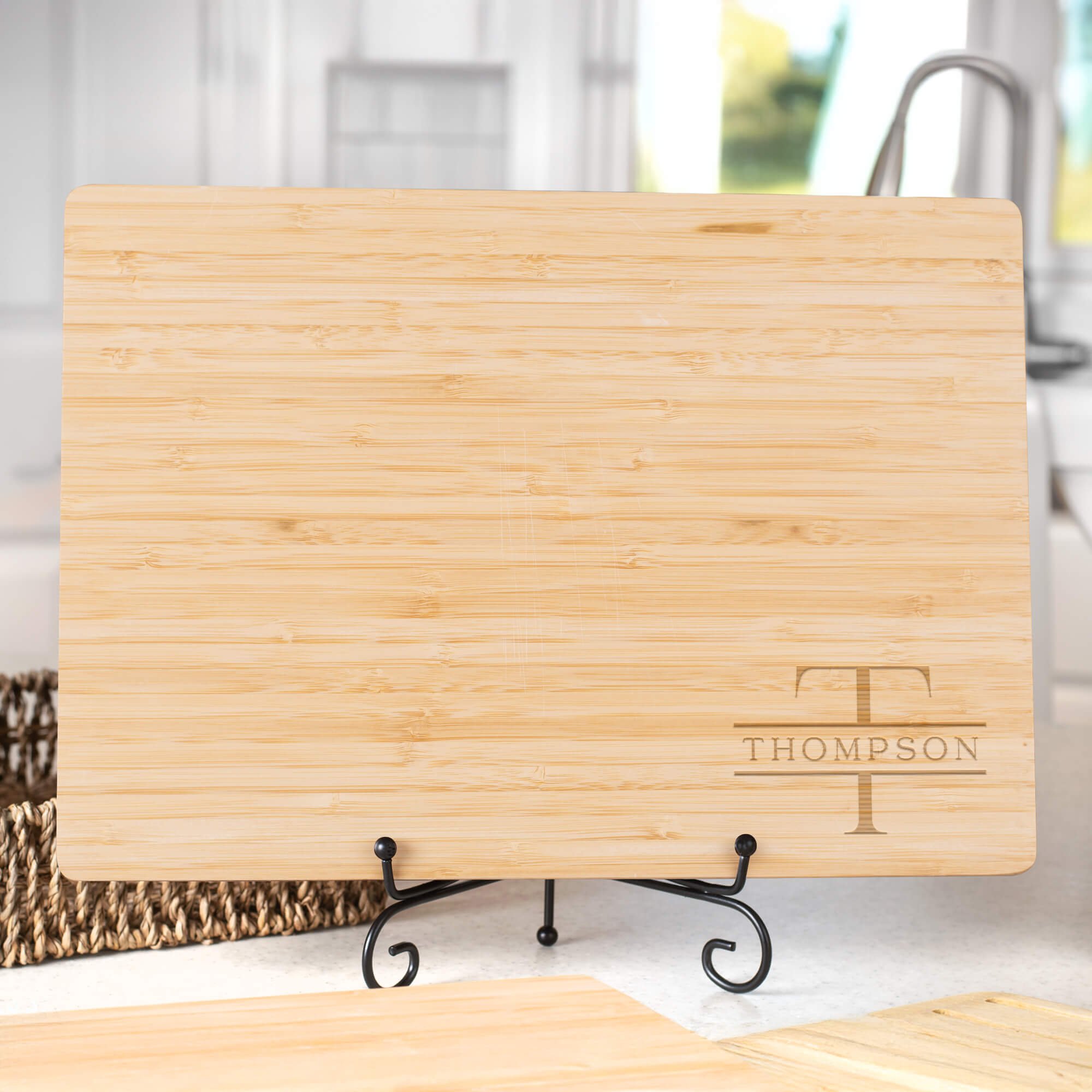 Custom Family Monogram Bamboo Cutting Board sitting on metal easel in a brightly lit kitchen