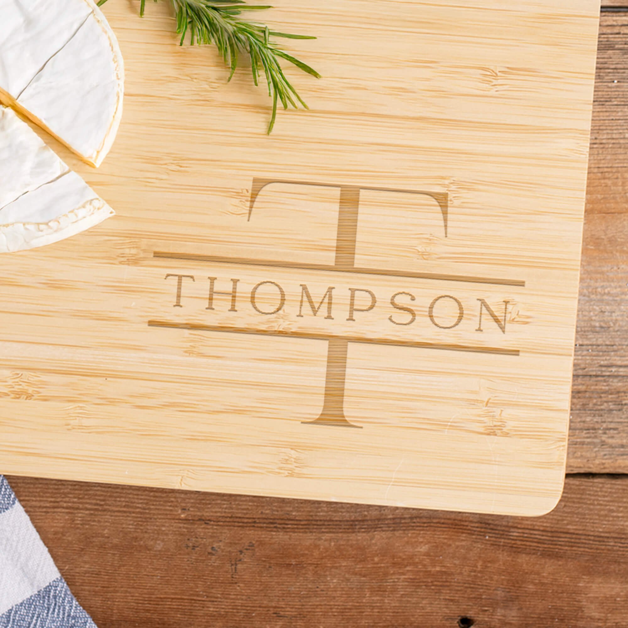 Custom Family Monogram Bamboo Cutting Board zoomed in on design next to brie cheese and rosemary