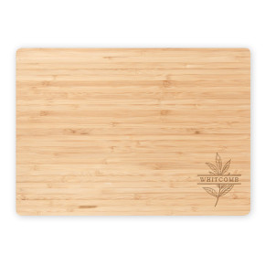 Flat lay of personalized bamboo cutting board featuring “Whitcomb” and a botanical leaf engraving on a clean white background.