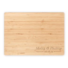 Flat lay of bamboo cutting board engraved with “Molly & Phillip” and date, shown on a white background for product detail view.