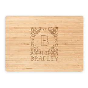 Engraved bamboo cutting board with detailed B monogram and Bradley name, isolated on white background