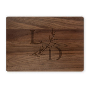 Walnut cutting board with serif L and D initials and botanical branch on white background