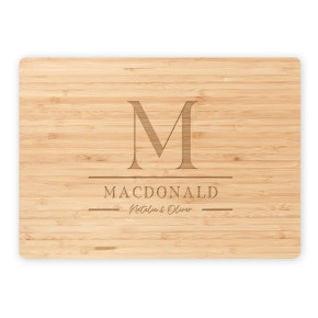 Bamboo cutting board featuring engraved M monogram, MacDonald family name, and script names Natalie & Oliver on white background