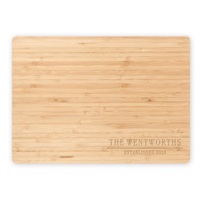 Flat lay of engraved bamboo cutting board with 'The Wentworths Established 2025' on a clean white background.