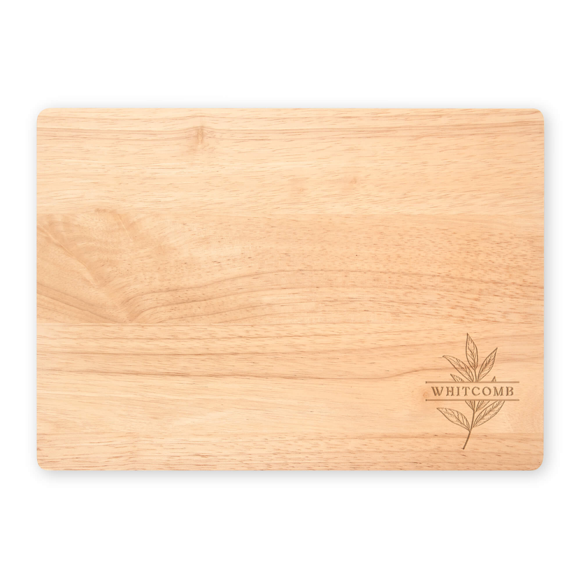 Flat lay of engraved maple cutting board with “Whitcomb” and a botanical leaf design, shown on a white background to highlight the natural wood tone.